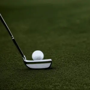 A close-up of a golf club head and ball in preparation for a swing
