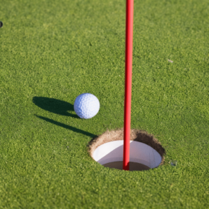 A golf ball positioned inches away from the hole