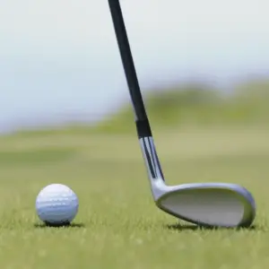 A golf club positioned to hit the ball