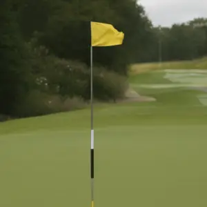 An image of a yellow golf flag waving in the breeze atop a metal pole
