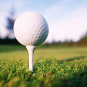 A close-up image o fa white golf tee supporting a golf ball