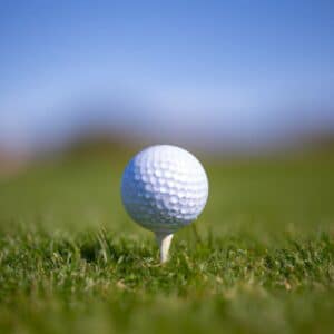 A golf ball sitting on a tee, placed on a green golf course