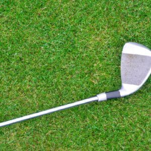 A golf club head lying on a grassy field