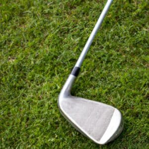A golf club rests on the grassy ground of a golf course