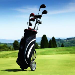 A golf trolley holding a golf bag with clubs on a green course