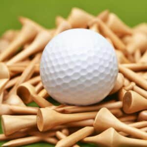 Close-up image of a white golf ball with visible dimples, lying on wooden tees.