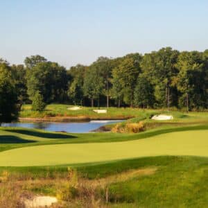 Scenic view of a golf course with green grass, sand traps, and water hazards surrounded by trees .