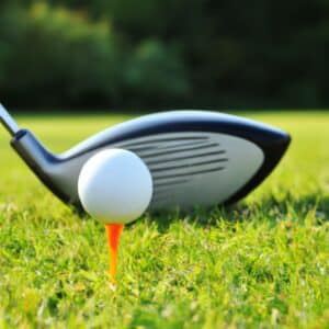 a golf driver and a golf ball on an orange tee