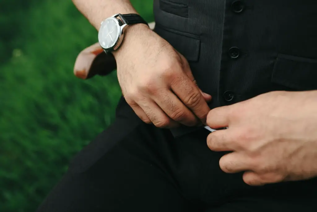 a person with watch buttoning vest