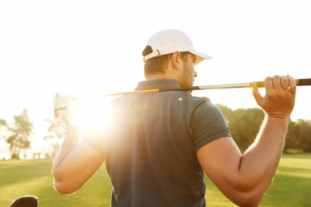 back view young man carrying golf club