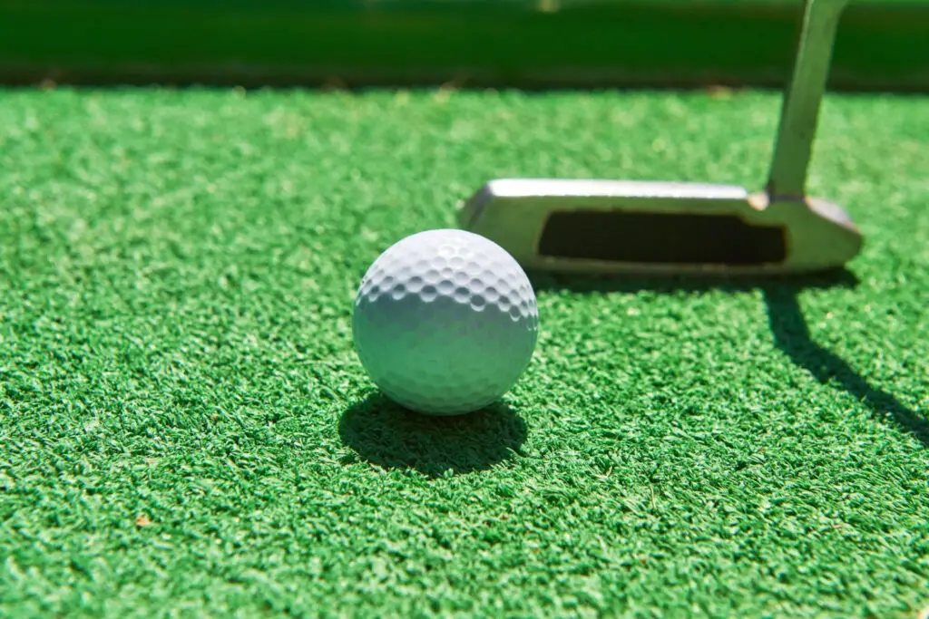 golf ball and golf club on green mat