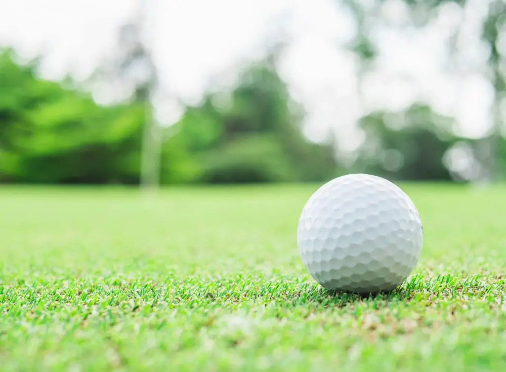 golf ball on green with blurred pin flagstick