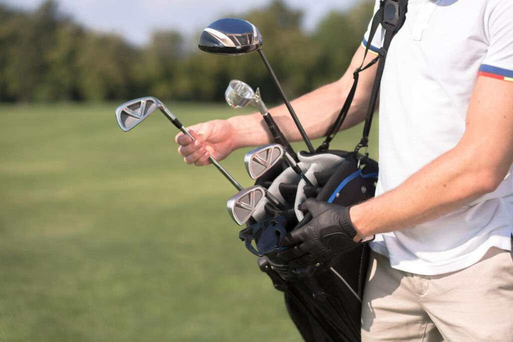 a man in white tshirt removing golf club from his golf bag