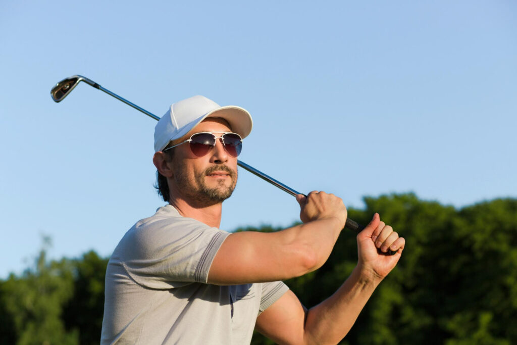 a man wearing shades cap holding a golf club