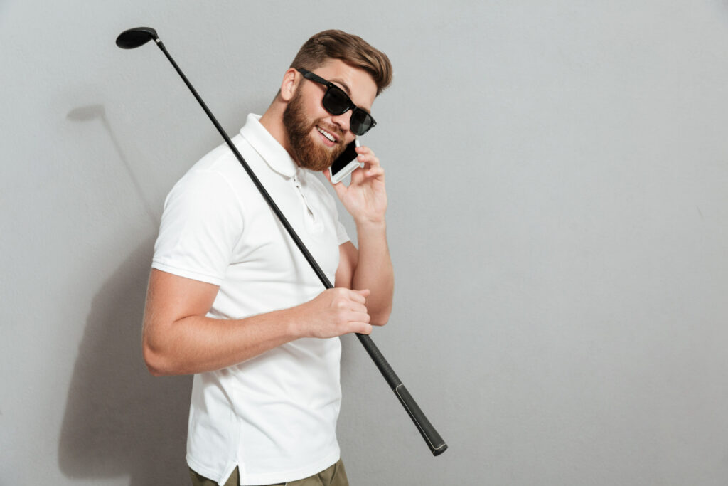 a man wearing shades holding a phone and club