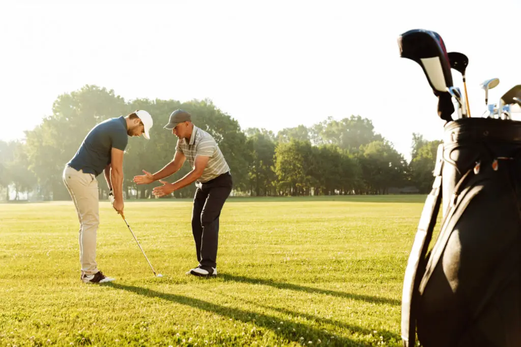 a sportsman practicing golf with his teacher