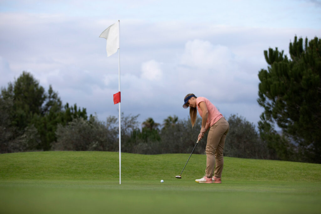 a woman aiming for golf flag