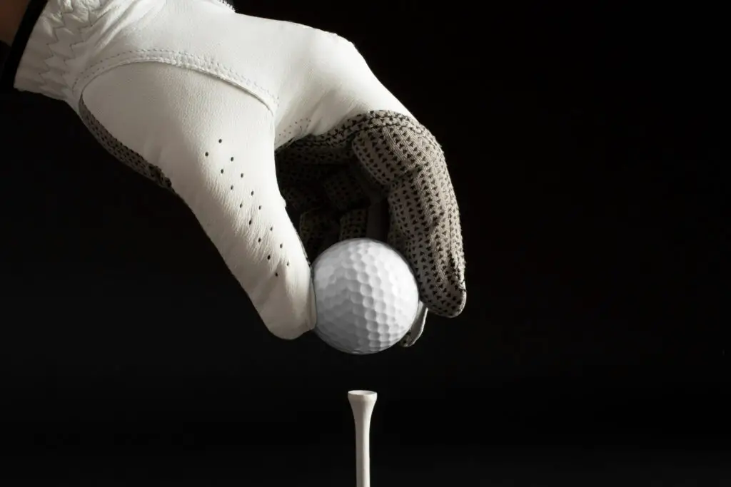hand with glove holding a golf ball